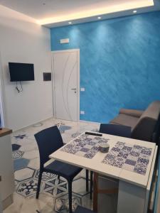 Habitación con mesa, sillas y pared azul. en Esposito Guest House en Procida