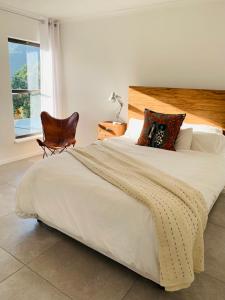 a bedroom with a large bed with a chair and a window at BEAUTIFUL VIEW Garden Apartment in Cape Town
