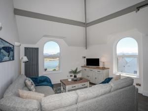 a living room with a couch and two windows at Gwynle - Criccieth in Criccieth