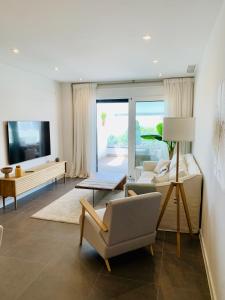 ein Wohnzimmer mit 2 Stühlen und einem TV in der Unterkunft Sea view luxury new apartment Marbella Port in Marbella