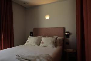 Schlafzimmer mit einem Bett mit weißer Bettwäsche und Kissen in der Unterkunft El Faro Unkempt - Tazones in Villar