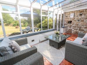 a conservatory with couches and a table and windows at Trevedran Cottage in Penzance