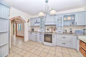 a kitchen with white cabinets and a tile floor at Casa Balena - Gansbaai seafront accommodation, back-up power in Gansbaai
