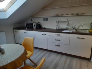 a kitchen with white cabinets and a table and a sink at Privat Magnolia in Mošovce