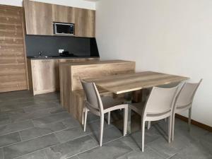 a kitchen with a wooden table and four chairs at Appartamento trilocale luxory,sulle piste da sci in Bormio