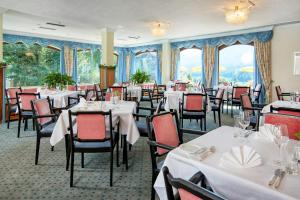 une salle à manger avec des tables et des chaises blanches dans l'établissement Hotel Schönruh, à Drobollach am Faakersee