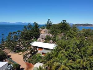 an aerial view of a house on a hill next to the ocean at The Boulders - Oceanfront Couple's Retreat with private pool near ferry in Nelly Bay