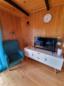 a living room with a chair and a clock on a wall at Domek Anna Zawóz in Zawóz