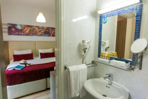 a bathroom with a sink and a bed at Fitosinn Hotel in Paphos