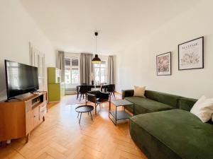 ein Wohnzimmer mit einem grünen Sofa und einem TV in der Unterkunft Stadtjuwel mit Pfänderblick in Bregenz
