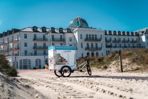 a bike parked on the beach in front of a building at Strandhotel Kurhaus Juist in Juist