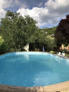 una grande piscina blu con alberi sullo sfondo di La Villa di Arezzo a San Zeno