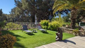 ラ・シオタにあるVilla Serenaの椅子2脚と傘1脚と芝生のある庭