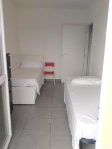 Habitación con 2 camas y silla roja. en Appartamento Eleonora, en Muscoline