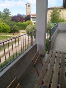 un banco de madera en un balcón con una torre de reloj en Appartamento Eleonora, en Muscoline