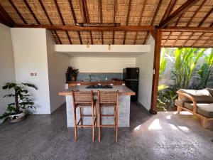 an open kitchen with a island with chairs and a table at Jati Kuta Lombok in Kuta Lombok