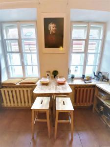 eine Küche mit einem Tisch, 2 Stühlen und Fenstern in der Unterkunft Jimmy Jumps House in Vilnius
