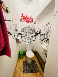 La salle de bains est pourvue de toilettes et de graffitis sur le mur. dans l'établissement Jimmy Jumps House, à Vilnius