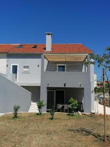 a white house with a table and chairs in a yard at Apartment Mimosa-Olib HR in Olib