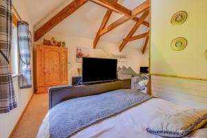 a bedroom with a bed and a tv on the wall at Little Torr in Drewsteignton