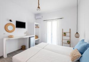 a white bedroom with a white bed and a tv at Dorkas Luxury Rooms&Apartments in Livadakia