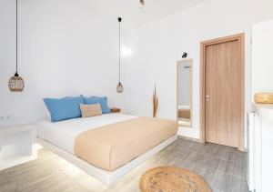 a white bedroom with a bed with blue accents at Dorkas Luxury Rooms&Apartments in Livadakia
