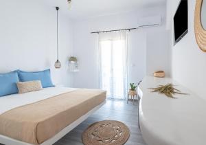 a white bedroom with a large bed and a rug at Dorkas Luxury Rooms&Apartments in Livadakia