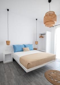 a white bedroom with a large bed with blue pillows at Dorkas Luxury Rooms&Apartments in Livadakia