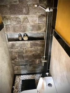 La salle de bains est pourvue de toilettes et d'un mur en pierre. dans l'établissement Ubud home stay, à Gianyar