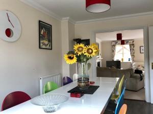 a living room with a table with a vase of sunflowers at Norwich City Large Modern Home in Norwich