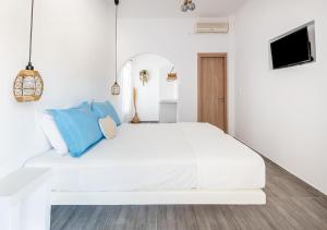 a white bedroom with a white bed with blue pillows at Dorkas Luxury Rooms&Apartments in Livadakia
