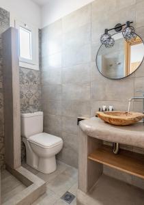 a bathroom with a toilet and a sink and a mirror at Dorkas Luxury Rooms&Apartments in Livadakia