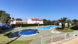 un ampio cortile con due piscine e palme di Apartamento Bellavista a Salou