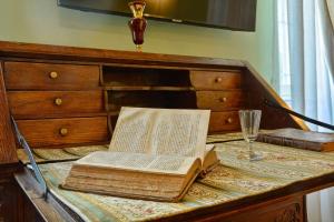 een open boek op een dressoir met een wijnglas bij History House in Corfu-stad