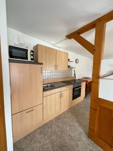 cocina con armarios de madera y microondas en Ferienwohnung am Kalkweg, en Bad Sooden-Allendorf