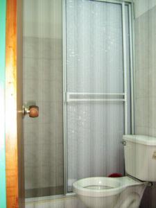a bathroom with a toilet and a glass shower at Hotel Arpa de Aguas in Villavicencio