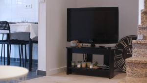 a living room with a television on a stand with a table at Agréable maison avec parking gratuit sur place. in Saint-Denis