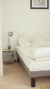 ein weißes Bett in einem Zimmer mit einer Lampe und einem Tisch in der Unterkunft Agréable maison avec parking gratuit sur place. in Saint-Denis