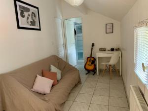a living room with a couch and a guitar at Agréable maison avec parking gratuit sur place. in Saint-Denis