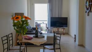 een woonkamer met een tafel met een vaas met bloemen bij KM Beach View apartment in Chania