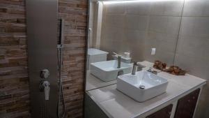 un bagno con due lavandini e uno specchio di KM Beach View apartment a Chania Altre 25 foto