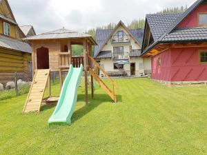 een speeltuin met een glijbaan in een tuin met huizen bij Willa Ewa in Poronin