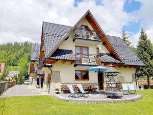 a house with chairs and an umbrella in front of it at Willa Ewa in Poronin