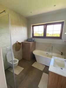 een badkamer met een bad, een toilet en een wastafel bij Pape Apartament in Pape