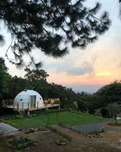 una casa en la cúpula en una colina con gente de pie en la cubierta en Casa Luna Glamping, en Sorá