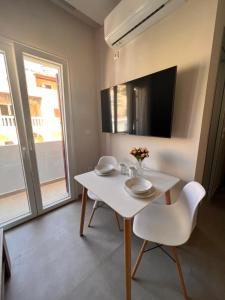 una mesa blanca y sillas en una habitación con TV en Astra Studios Karpathos Island en Kárpatos