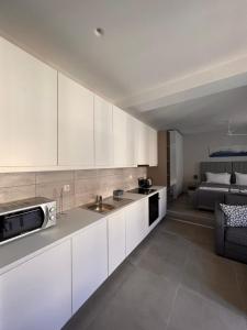 une cuisine avec des placards blancs et un lit en arrière-plan dans l'établissement Astra Studios Karpathos Island, à Karpathos