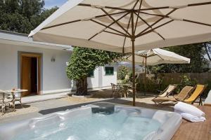 a hot tub with an umbrella on a patio at Montespina Park Hotel in Naples