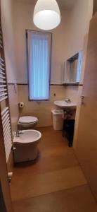 a bathroom with a toilet and a sink and a window at CASA VACANZA IL BALCONCINO in Bergamo
