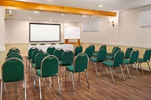 a conference room with a white table and green chairs at Howard Johnson by Wyndham Gravenhurst in Gravenhurst